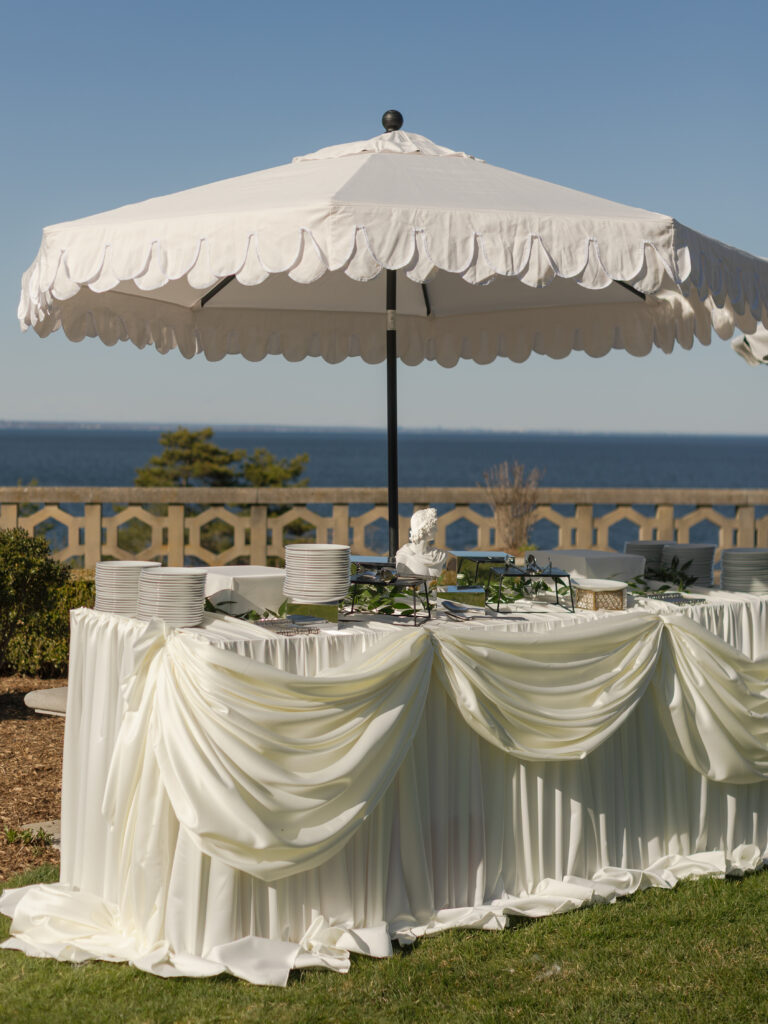 Cocktail hour table with romantic draping and umbrellas at a Hempstead House wedding