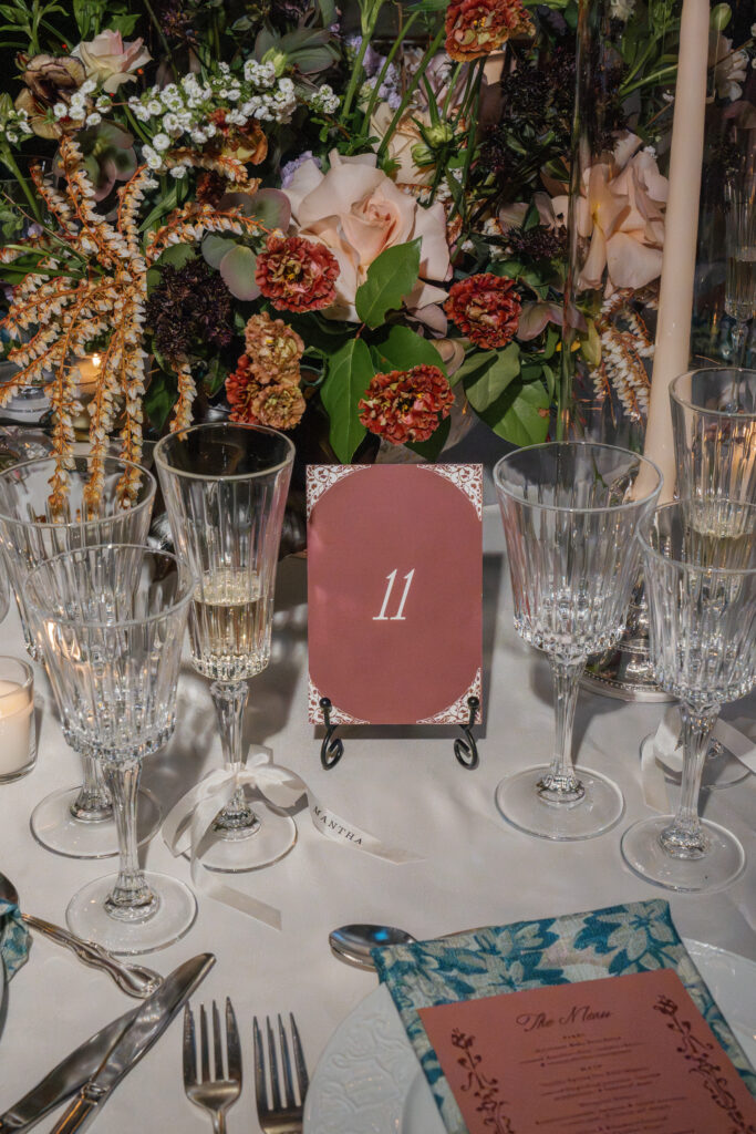 Custom burgundy wedding table number styled with florals and taper candles